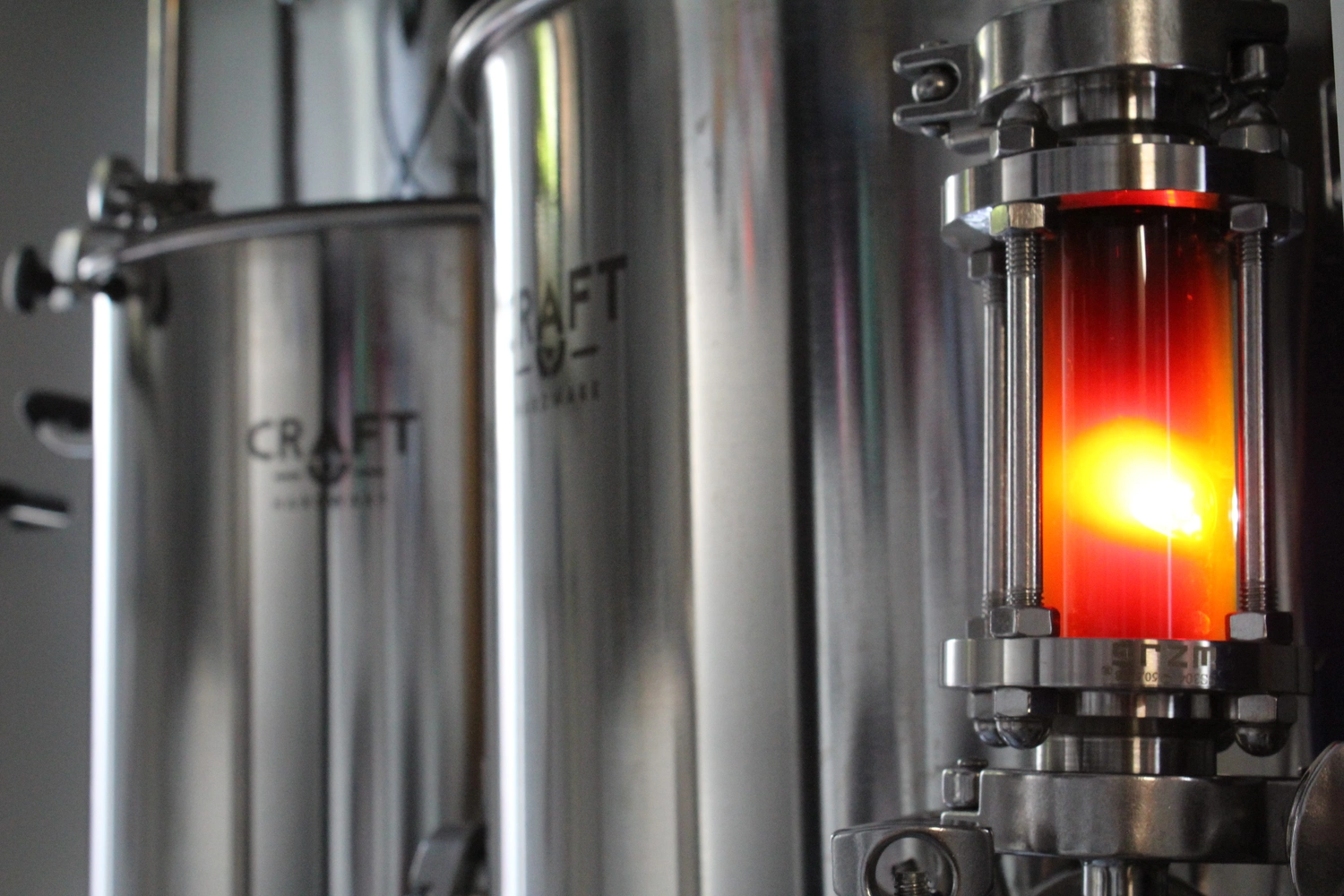 Lessigs Brauwerkstatt GmbH – Das abgebildete Objekt ist ein industrielles Schauglas zur Überwachung von Durchfluss und Qualität einer Flüssigkeit, beispielsweise Bier, während des Brauprozesses.